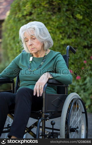 Depressed Senior Woman In Wheelchair Sitting Outdoors