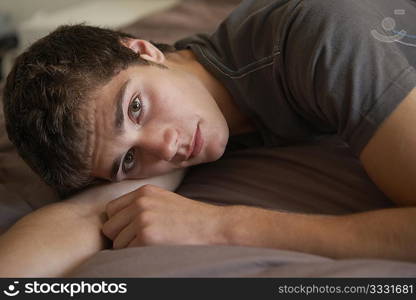 Depressed Teenage Boy Lying In Bedroom