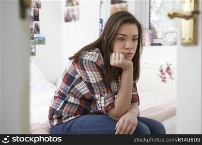Depressed Teenage Girl Sitting In Bedroom