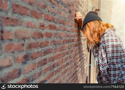 Depressed teenage woman feeling sad alone against brick wall in old town. Education and family failure concept.