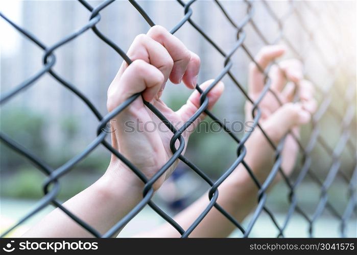 Depressed, trouble and solution. Women hand on chain-link fence.
