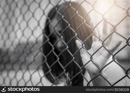 Depressed, trouble, help and chance. Hopeless women raise hand o. Depressed, trouble, help and chance. Hopeless women raise hand on chain-link fence ask for help