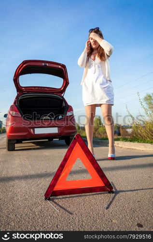 Depressed woman calling phone near crashed car