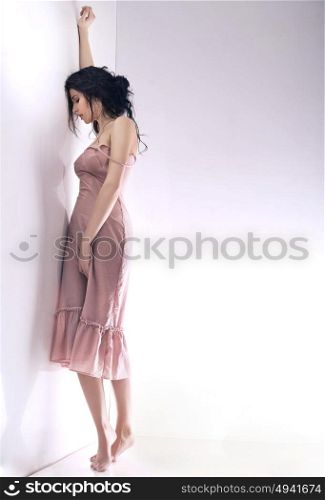 Depressed woman leaning against the bright wall
