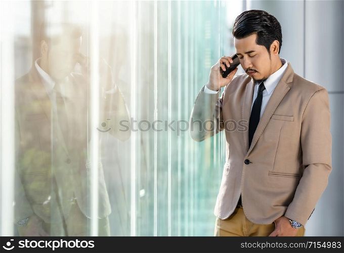 depressed young business man is talking on smartphone in office