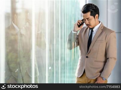 depressed young business man is talking on smartphone in office