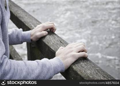 Depressed Young Man Contemplating Suicide On Bridge Over River