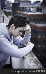 Depressed Young Man Contemplating Suicide On Top Of Tall Building