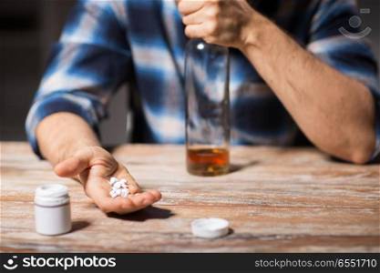 depression, drug abuse and addiction people concept - unhappy drunk man with bottle of alcohol and pills committing suicide by overdosing on medication at night. unhappy drunk man with bottle of alcohol and pills. unhappy drunk man with bottle of alcohol and pills