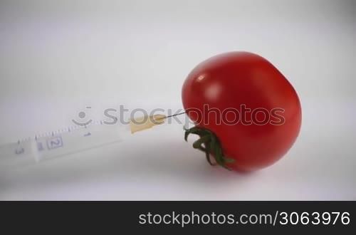 Der Fokus wandert von einer frischen glatten Tomate mit einer Spritze zu einer alten faltigen runzeligen Tomate. Focus moves from a fresh tomato with a syringe to an old tomato with wrinkles.