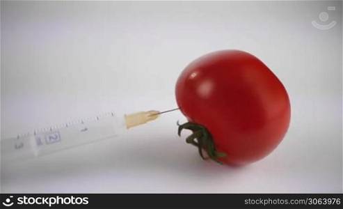 Der Fokus wandert von einer frischen glatten Tomate mit einer Spritze zu einer alten faltigen runzeligen Tomate. Focus moves from a fresh tomato with a syringe to an old tomato with wrinkles.