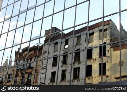 Derelict buildings reflected in modern office tower in New York&rsquo;s Chinatown