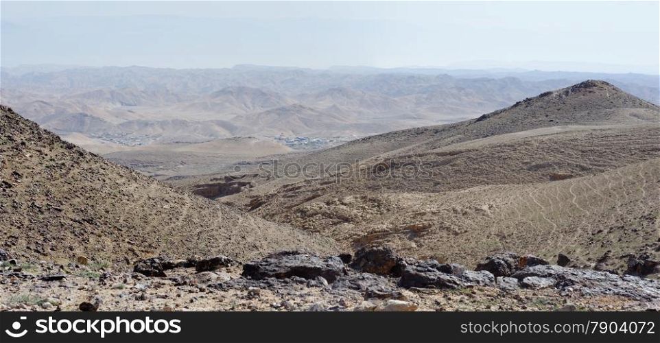 Desert landscape with far Bedouin camp on hazy day in Kidod Ceek near Arad in Negev desert, Israel. Desert landscape with far Bedouin camp on hazy day