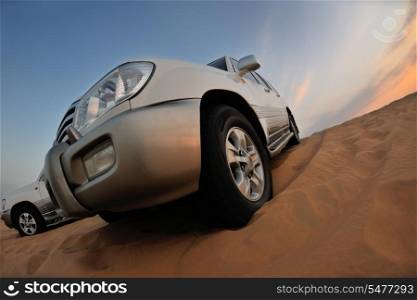 Desert Safari - Off-road jeep vehicles driving in the Arabian Desert at sunset