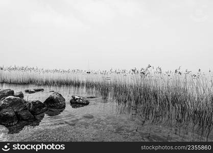 Deserted shore of Lake Garda in Italy in the absence of tourism in black and white.