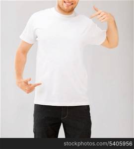 design and advertisement concept - picture of smiling man pointing at blank white t-shirt