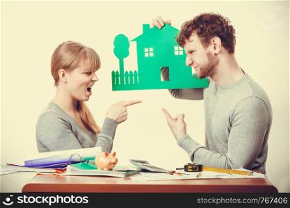 Design property family ownership real estate concept. Young couple arguing about future. Man and woman holding house model discussing plans.. Young couple arguing about future.