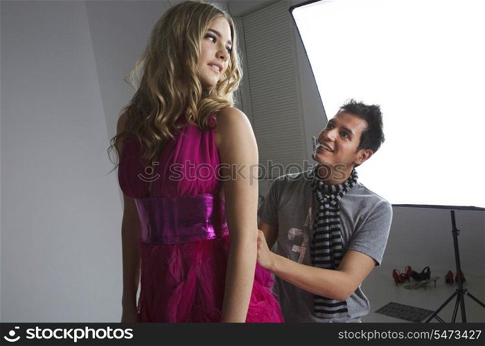 Designer adjusting fashion model&rsquo;s dress in studio