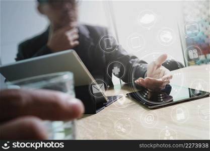Designer Businessman hand using smart phone,mobile payments online shopping,omni channel,digital tablet docking keyboard computer in modern office on wooden desk,virtual interface icons screen