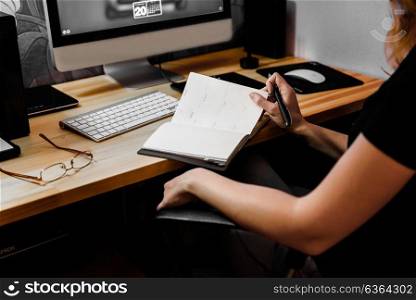 designer girl at work at the table draws on the tablet, close the keypad, printer, computer