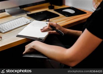 designer girl at work at the table draws on the tablet, close the keypad, printer, computer