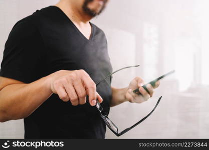 Designer hand holding eyeglasses,using smart phone on white background,filter effect