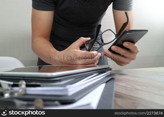 Designer hand using mobile payments online shopping,omni channel,in modern office wooden desk,icons graphic interface screen,eyeglass