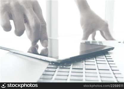 designer hand working and digital tablet and laptop on wooden desk in office