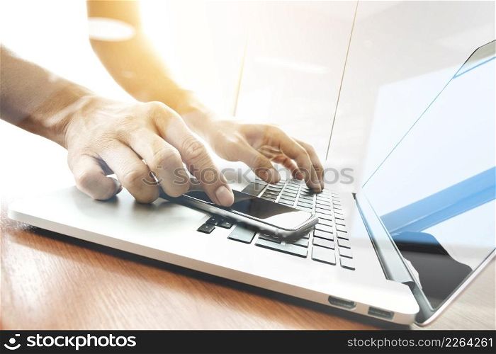 designer hand working and smart phone and laptop on wooden desk