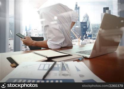 designer hand working and smart phone and laptop on wooden desk in office with london city background