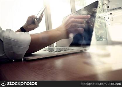 designer hand working and smart phone and laptop on wooden desk in office background with social network diagram