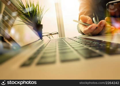 designer hand working and smart phone and laptop on wooden desk in office with london city background