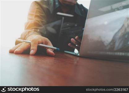designer hand working and smart phone and laptop on wooden desk in office as concept