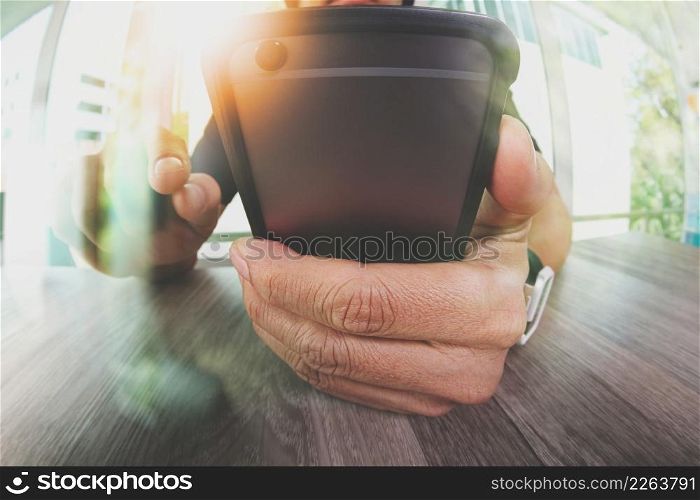 designer hand working and smart phone on wooden desk in office