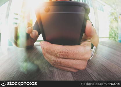 designer hand working and smart phone on wooden desk in office