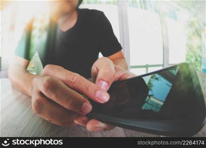 designer hand working and smart phone on wooden desk in office