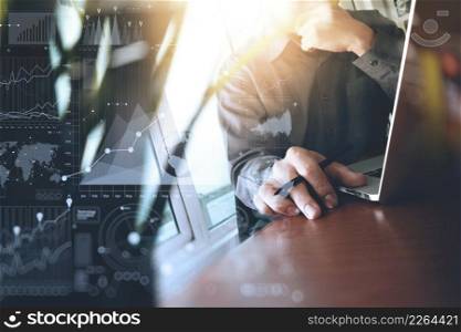 designer hand working laptop with green plant foreground on wooden desk in office