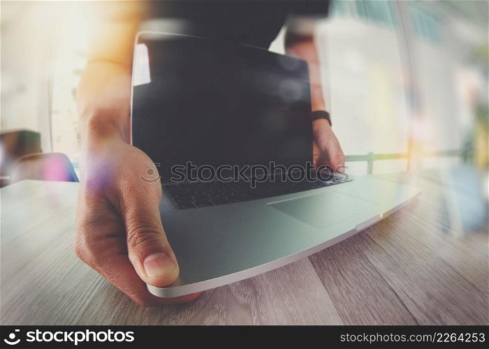 Designer hand working with blank screen laptop computer on wooden desk as responsive web design concept