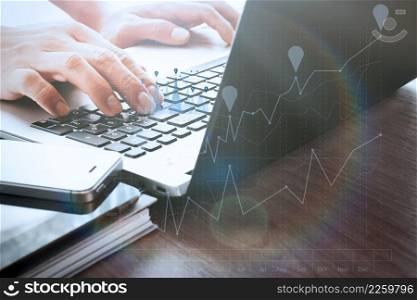 designer hand working with digital tablet and laptop and notebook stack and eye glass on wooden desk in office with business graph diagram
