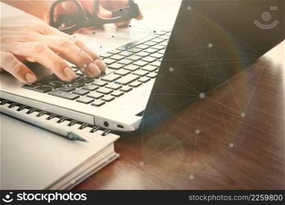designer hand working with digital tablet and laptop and notebook stack and eye glass on wooden desk in office with social media diagram