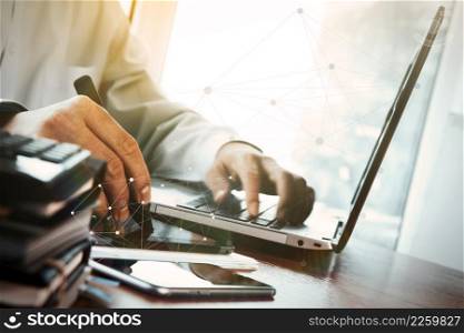 designer hand working with digital tablet and laptop and notebook stack and eye glass on wooden desk in office with social media diagram