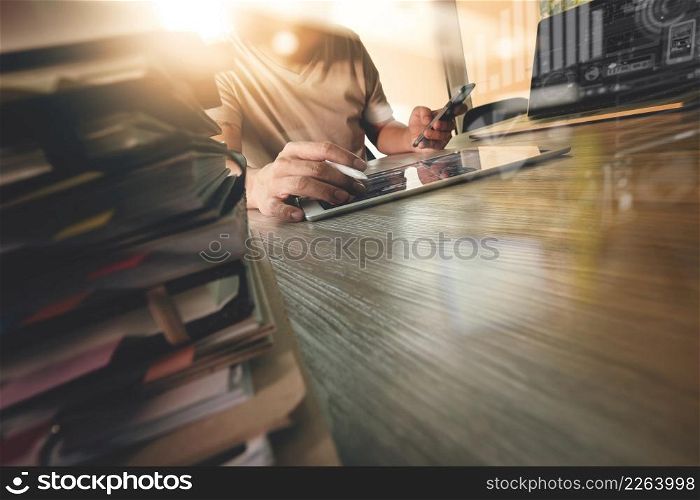designer hand working with digital tablet and laptop computer and book stack on wooden desk as concept
