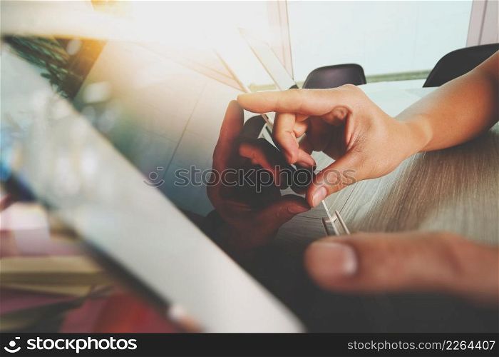 designer hand working with digital tablet and laptop computer and book stack and eye glass on wooden desk as concept