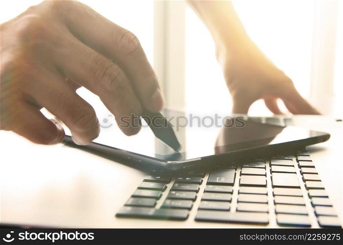 designer hand working with stylus and digital tablet and laptop on wooden desk in office