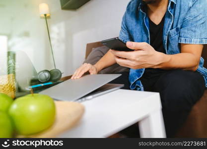 designer man hand using laptop compter and mobile payments online shopping,omni channel,sitting on sofa in living room,green apples in wooden tray,filter