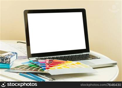 designer&rsquo;s working table - open notebook with empty screen and colour charts guide. designer&rsquo;s working table