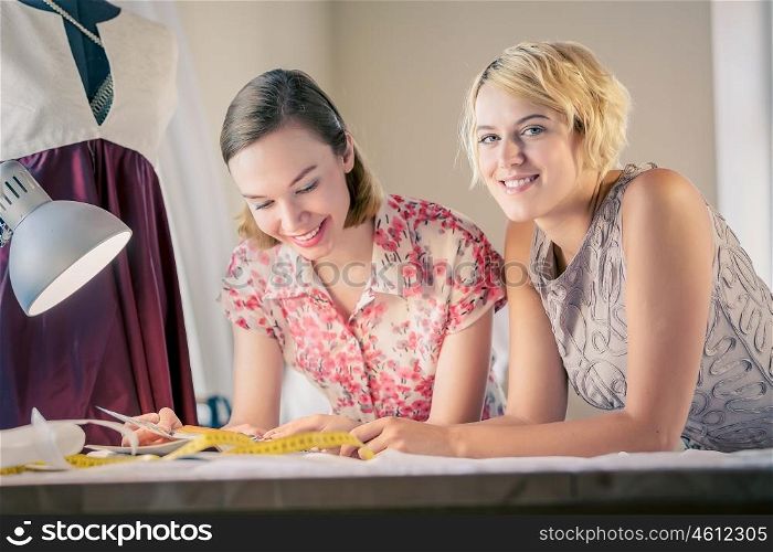 Designers at work. Two young women dressmakers at tailors studio