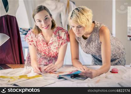 Designers at work. Two young women dressmakers at tailors studio
