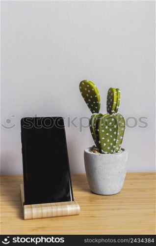 desk with black smartphone cactus plant