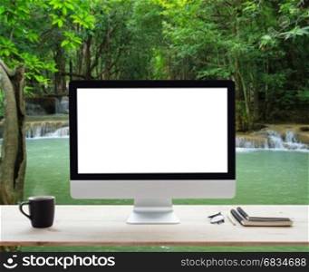 desktop computer white frame on work table and waterfall nature background